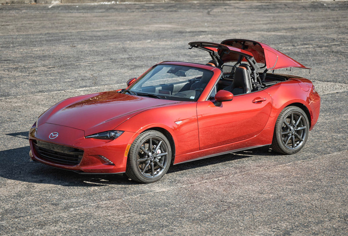 Mazda MX-5 Roadster displayed with its convertible roof open, showcasing its sleek design and sporty interior.