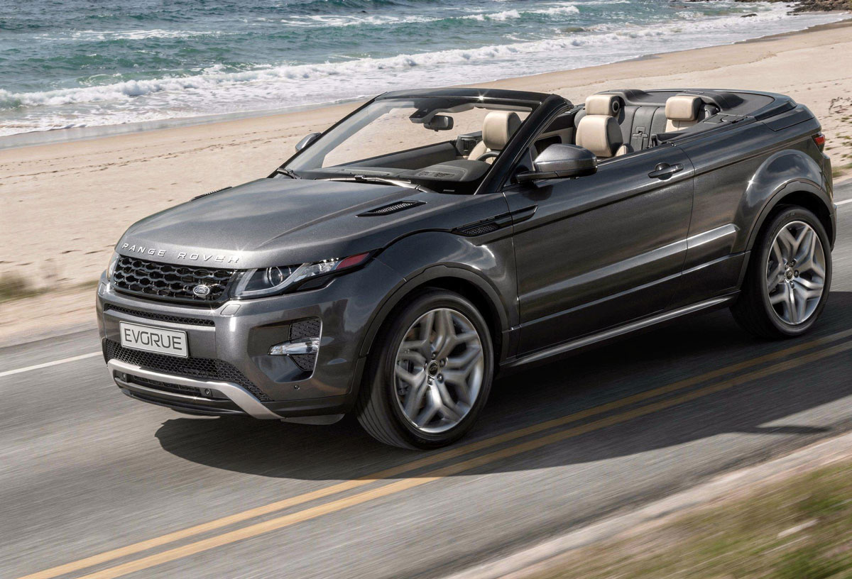A Range Rover convertible drives along a scenic road, showcasing its sleek design and open-top feature.