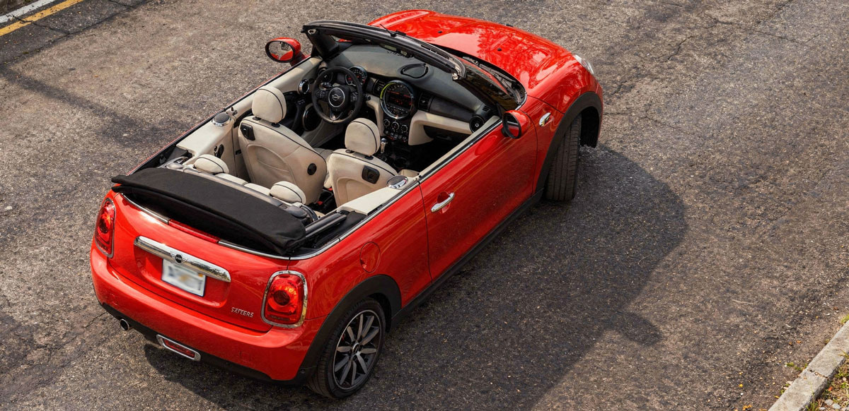 Mini Cooper convertible parked on a city street, showcasing its sleek design and vibrant color.