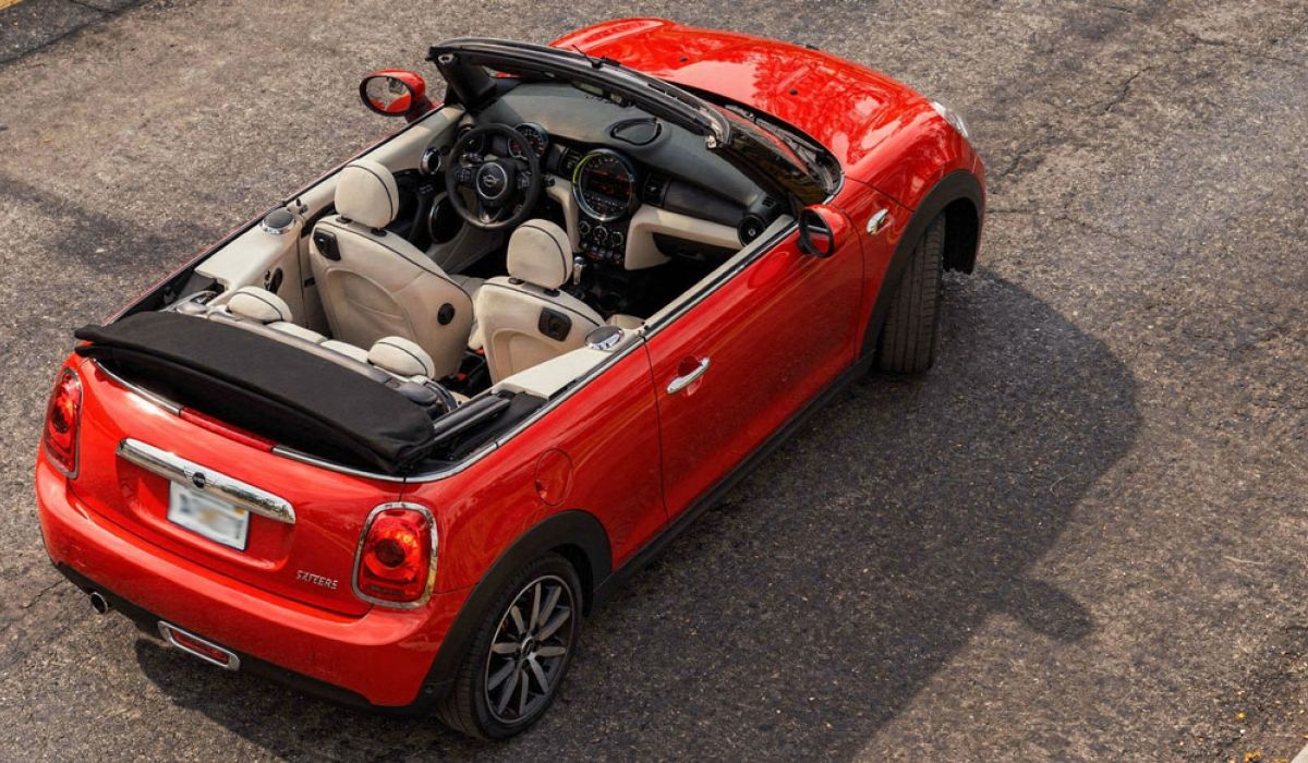 Mini Cooper convertible parked on a city street, showcasing its sleek design and vibrant color.