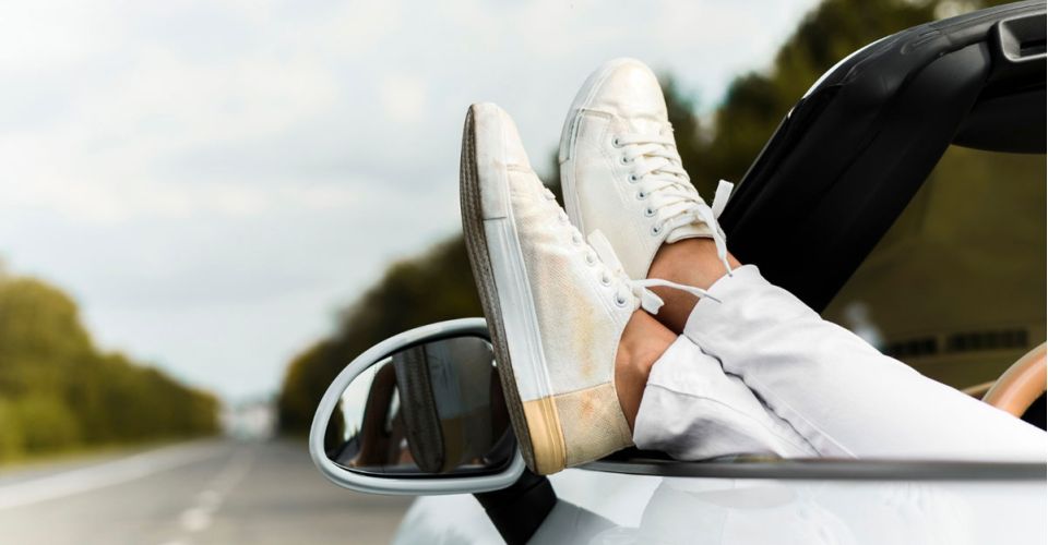 A person's feet resting on the dashboard of a car, showcasing a relaxed driving position.
