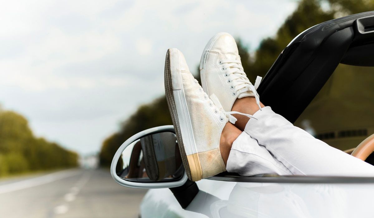 A person's feet resting on the dashboard of a car, showcasing a relaxed driving position.