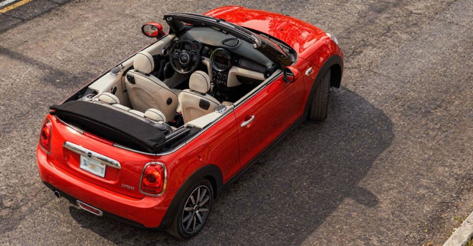 Mini Cooper convertible parked on a city street, showcasing its sleek design and vibrant color.
